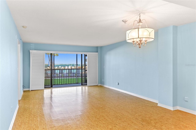 2700 N Peninsula Ave Unit 215, New Smyrna Beach, FL 32169 - spare room featuring wood finished floors, baseboards, and an inviting chandelier