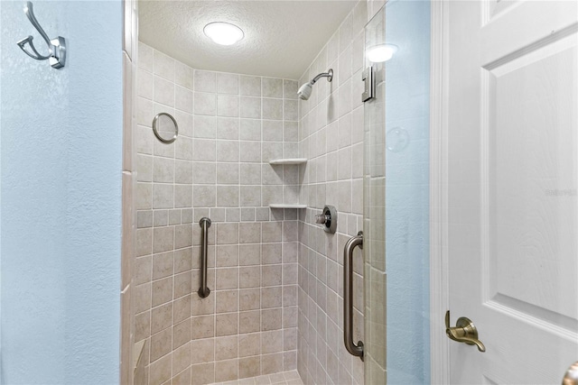 2700 N Peninsula Ave Unit 215, New Smyrna Beach, FL 32169 - bathroom with a textured wall, a textured ceiling, and a stall shower