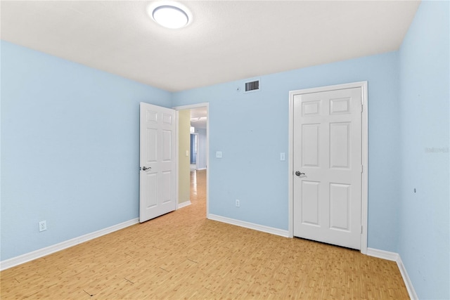 2700 N Peninsula Ave Unit 215, New Smyrna Beach, FL 32169 - unfurnished bedroom with light wood-type flooring, visible vents, and baseboards