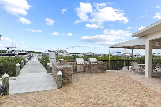 2700 N Peninsula Ave Unit 215, New Smyrna Beach, FL 32169 - view of patio / terrace featuring fence, grilling area, outdoor dining space, and exterior kitchen