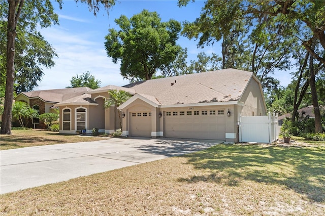 2082 Nexus Ct, Apopka, FL 32712 - view of front of house with an attached garage, driveway, a gate, a front lawn, and stucco siding