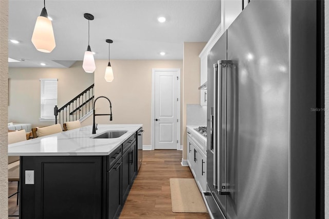 10215 Park Estates Ave, Orlando, FL 32836 - kitchen with light wood finished floors, a sink, a center island with sink, appliances with stainless steel finishes, and a breakfast bar area