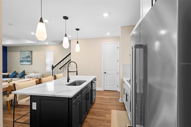 10215 Park Estates Ave, Orlando, FL 32836 - kitchen featuring stainless steel appliances, a sink, decorative light fixtures, a kitchen island with sink, and light wood-style flooring