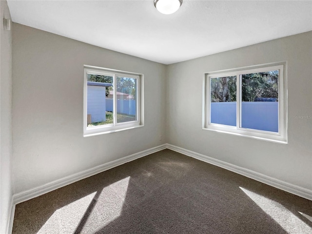unfurnished room with dark carpet and baseboards