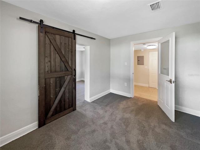 spare room featuring electric panel, carpet floors, visible vents, a barn door, and baseboards