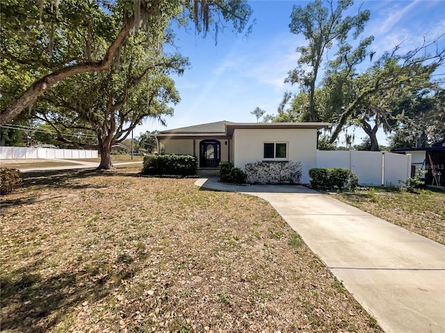 view of front of house with stucco siding, fence, and a front lawn