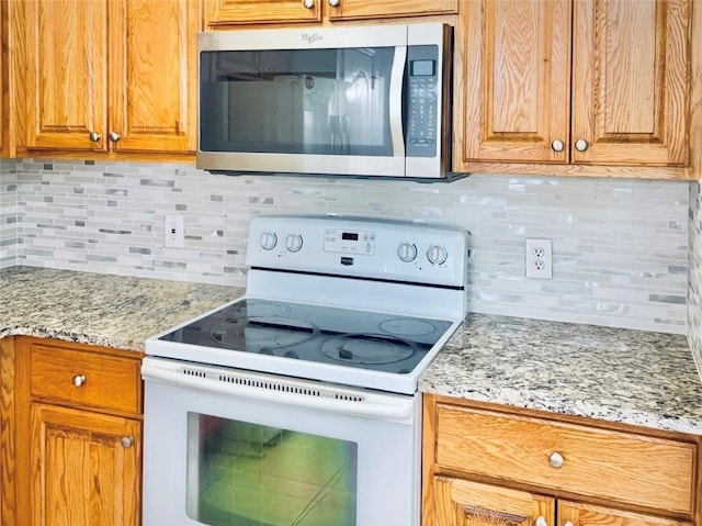 kitchen with tasteful backsplash, light stone counters, stainless steel microwave, brown cabinets, and white electric range oven