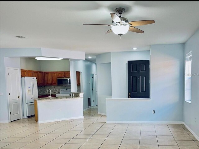 kitchen featuring tasteful backsplash, white refrigerator with ice dispenser, stainless steel microwave, electric range oven, and ceiling fan