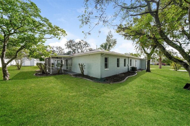 10237 Bannock St, Spring Hill, FL 34608 - rear view of property with a lawn, central AC unit, a sunroom, and stucco siding