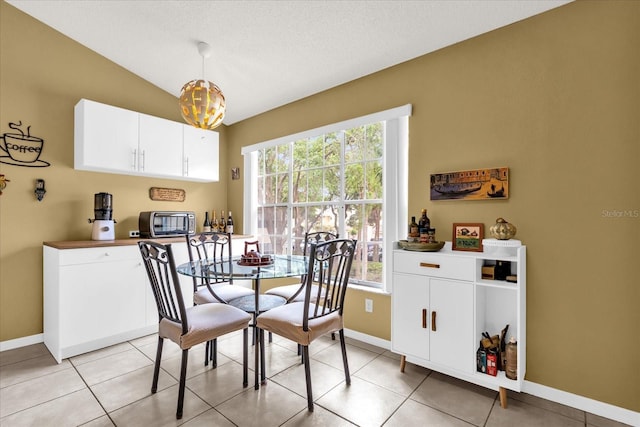 dining space with light tile patterned floors, baseboards, vaulted ceiling, and a wealth of natural light