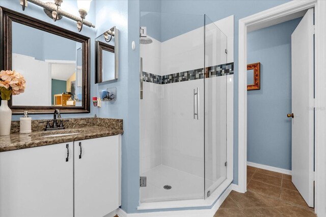 full bathroom with a shower stall, baseboards, vanity, and tile patterned flooring