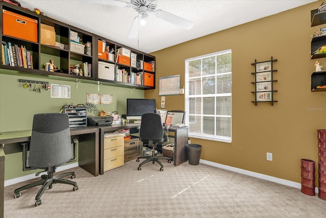 office featuring built in desk, baseboards, carpet floors, and ceiling fan