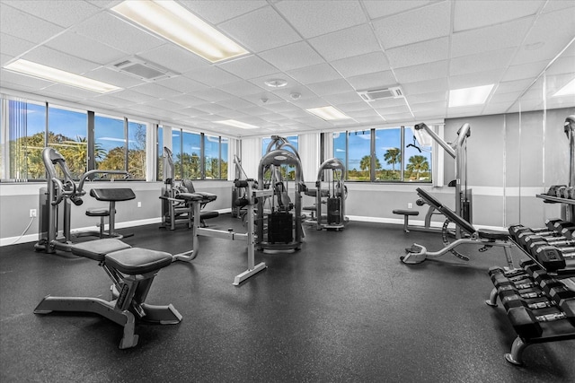 workout area with visible vents, a paneled ceiling, and baseboards