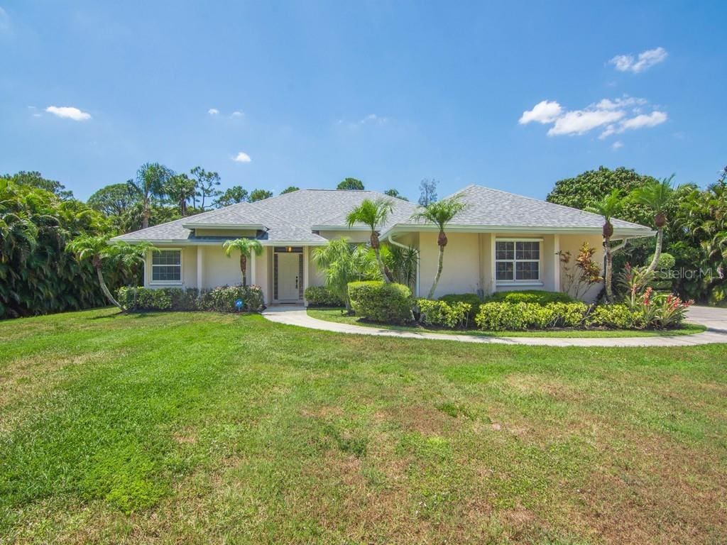 ranch-style home featuring a front lawn and stucco siding