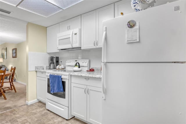 kitchen featuring white cabinets, light countertops, visible vents, white appliances, and tasteful backsplash