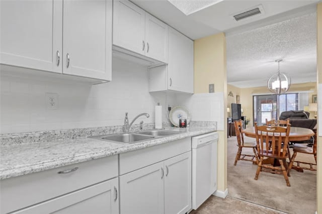 kitchen featuring a sink, visible vents, white cabinetry, decorative backsplash, and white dishwasher