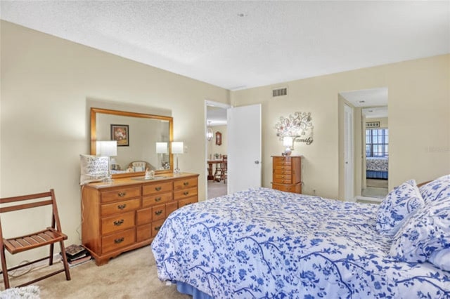 bedroom with visible vents, a textured ceiling, and light colored carpet