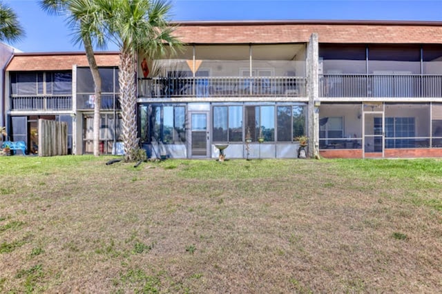 rear view of property featuring a lawn and a sunroom
