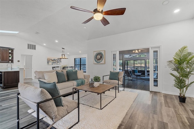 living area featuring vaulted ceiling, ceiling fan, light wood-style flooring, visible vents, and recessed lighting