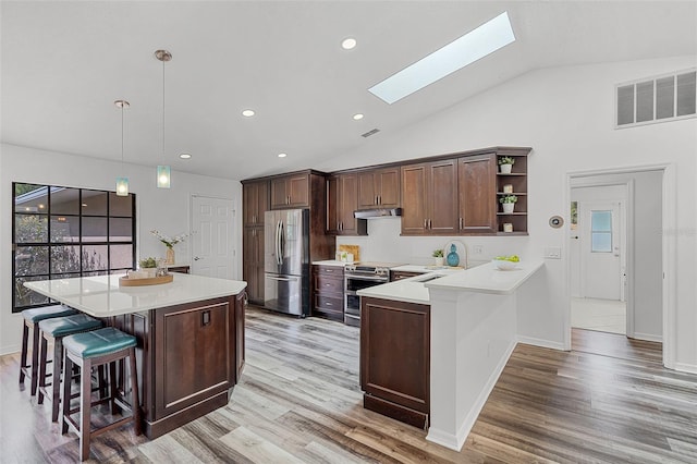 kitchen with a skylight, stainless steel appliances, light countertops, under cabinet range hood, and visible vents