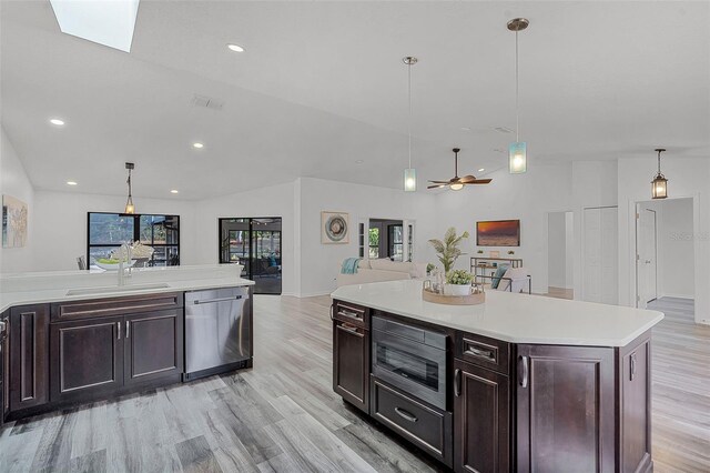 kitchen featuring light countertops, a sink, light wood-style floors, appliances with stainless steel finishes, and open floor plan