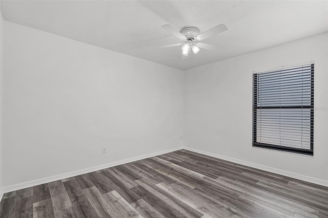 empty room with dark wood finished floors, baseboards, and ceiling fan