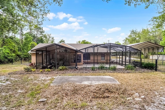 back of house with a lanai, fence, and a carport