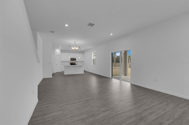 unfurnished living room with a chandelier, visible vents, dark wood-type flooring, and recessed lighting