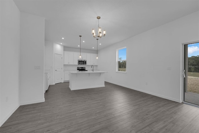 kitchen with stainless steel appliances, white cabinetry, dark wood-type flooring, open floor plan, and a notable chandelier