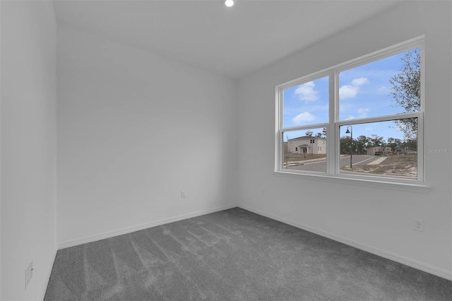 unfurnished room featuring dark carpet, baseboards, and a healthy amount of sunlight