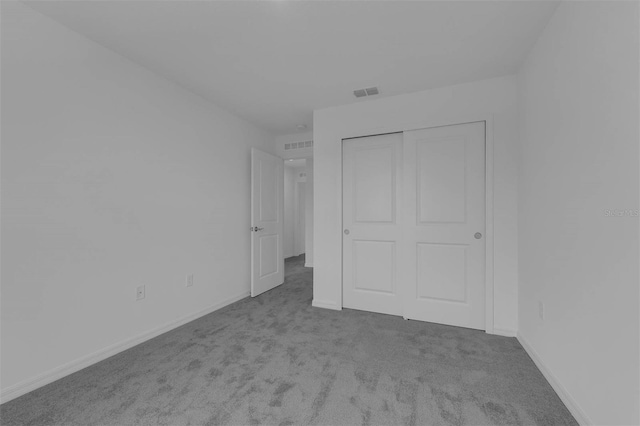 unfurnished bedroom with carpet floors, a closet, visible vents, and baseboards