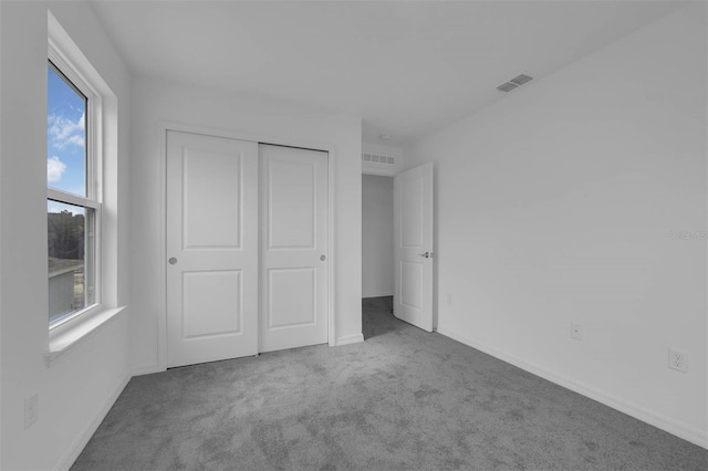 unfurnished bedroom featuring baseboards, visible vents, carpet floors, and a closet