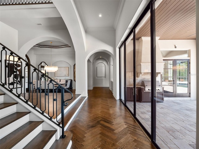 foyer entrance with stairs, arched walkways, an inviting chandelier, baseboards, and ornamental molding