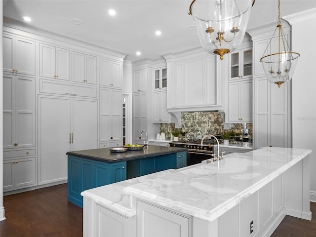 kitchen with high end stainless steel range, a spacious island, a chandelier, white cabinetry, and recessed lighting