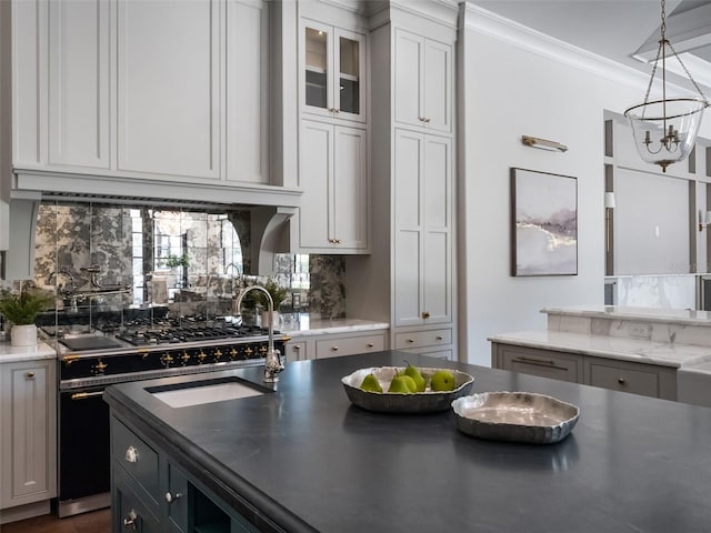 kitchen with high end range, tasteful backsplash, pendant lighting, and an inviting chandelier