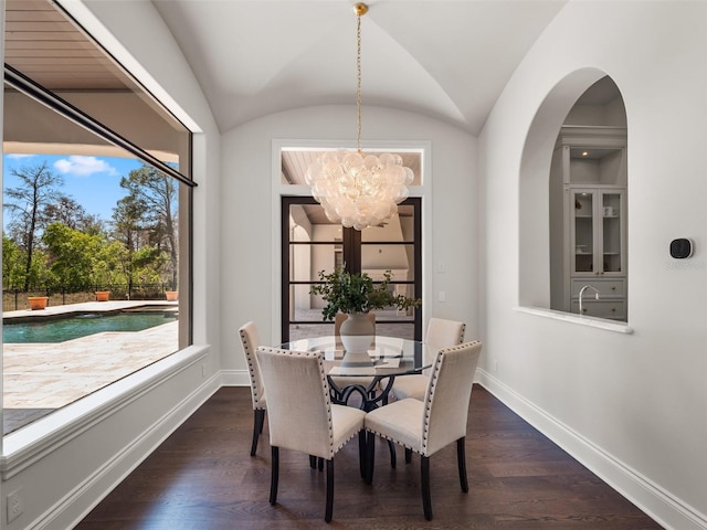 dining space with vaulted ceiling, baseboards, a notable chandelier, and dark wood-type flooring