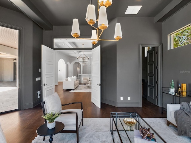 living area with baseboards, wood finished floors, arched walkways, and a notable chandelier
