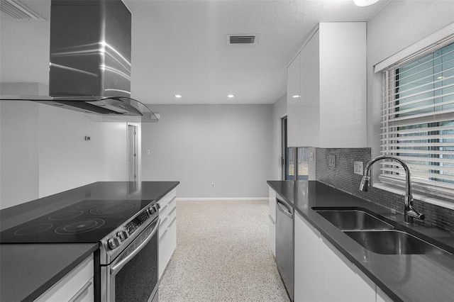 kitchen featuring island exhaust hood, a sink, appliances with stainless steel finishes, and dark countertops