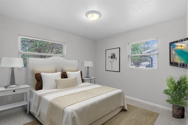 bedroom featuring light speckled floor and baseboards