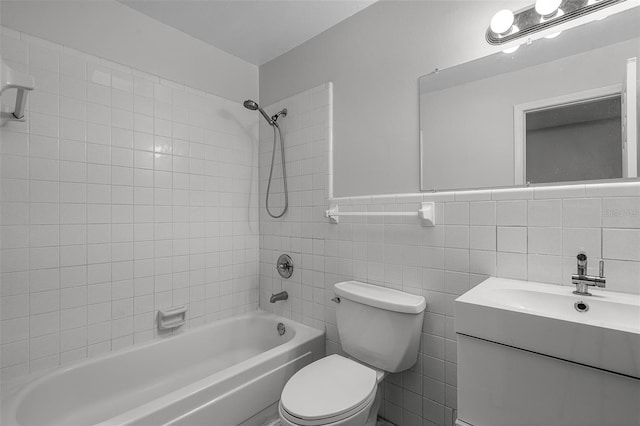 bathroom with vanity, toilet, tile walls, shower / bathing tub combination, and a wainscoted wall