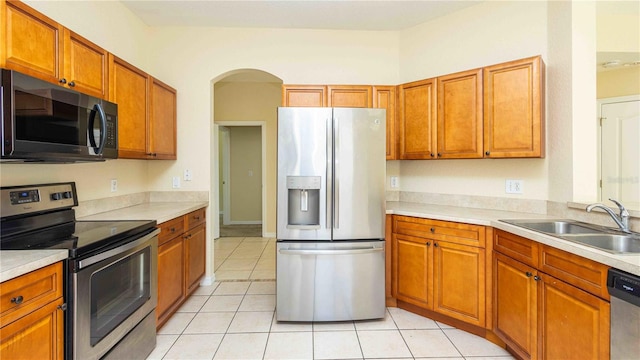1204 Blackheath Ct, Davenport, FL 33897 - kitchen with stainless steel appliances, arched walkways, light countertops, and brown cabinetry
