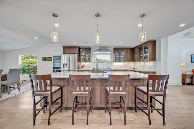 1661 Woodland Ave, Winter Park, FL 32789 - kitchen featuring light stone countertops, stainless steel fridge, backsplash, a spacious island, and glass insert cabinets