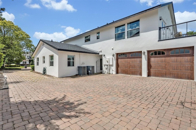 1661 Woodland Ave, Winter Park, FL 32789 - back of house featuring decorative driveway, a garage, stucco siding, and central air condition unit