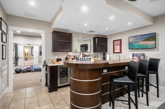 bar with recessed lighting, light colored carpet, indoor wet bar, and light tile patterned floors