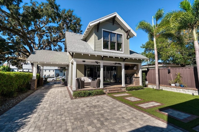 rear view of house with decorative driveway, outdoor lounge area, fence, roof with shingles, and ceiling fan