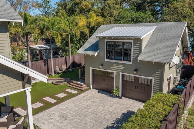 view of front facade featuring a garage, roof with shingles, fence, and decorative driveway
