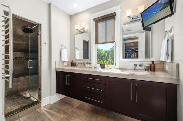 bathroom with double vanity, a shower stall, baseboards, and a sink