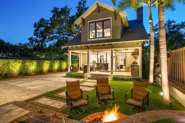 back of house featuring a chimney, fence, ceiling fan, a patio, and a fire pit