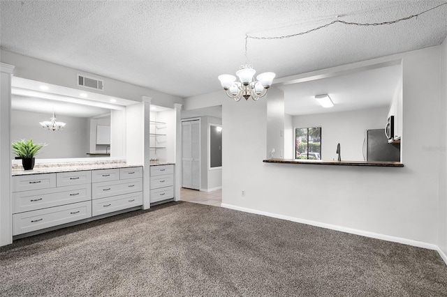 11 Escondido Cir Unit 110, Altamonte Springs, FL 32701 - kitchen featuring a chandelier, carpet, stainless steel microwave, refrigerator, and decorative light fixtures