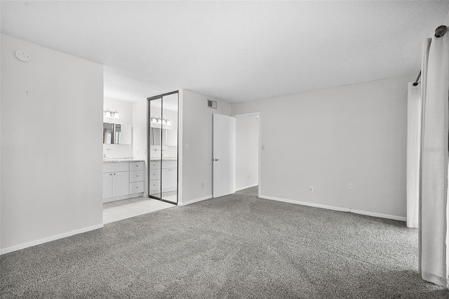 11 Escondido Cir Unit 110, Altamonte Springs, FL 32701 - unfurnished bedroom with light carpet, connected bathroom, and a textured ceiling